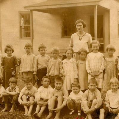 Teacher and students outside their one-room schoolhouse. Many poor families had to choose between buying their children shoes or school books.