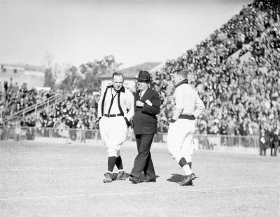 Huey Long on the gridiron with referees before a Louisiana State University football game.